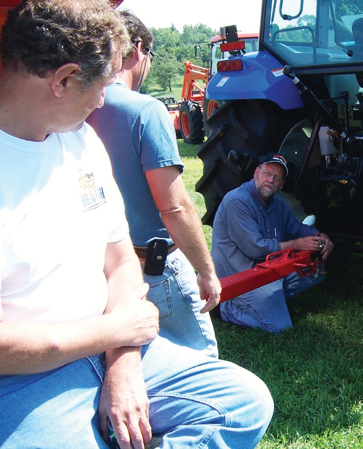 A loaded wagon and implement being inspected by a man